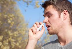 Mann mit Nasenspray bei allergischem Schnupfen